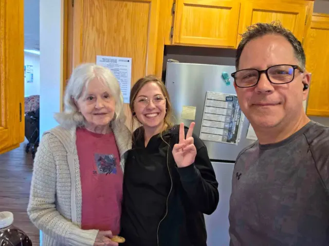Resident and staff smiling together in the kitchen at AAA Shepherd’s Care Home