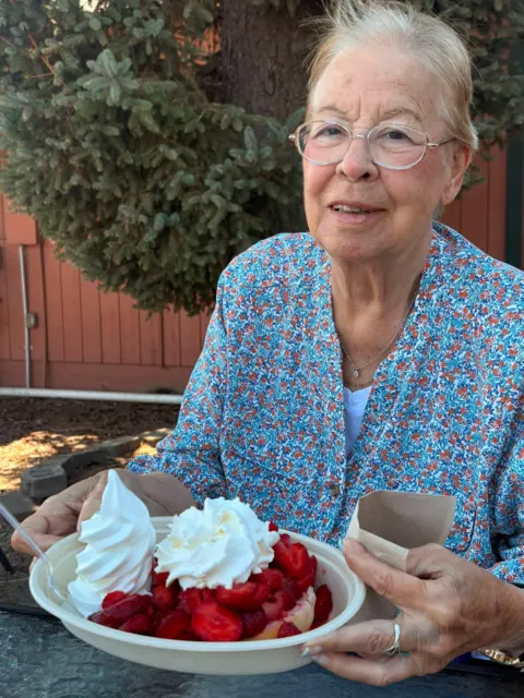 Resident enjoying a strawberry dessert outdoors at AAA Shepherd’s Care Home
