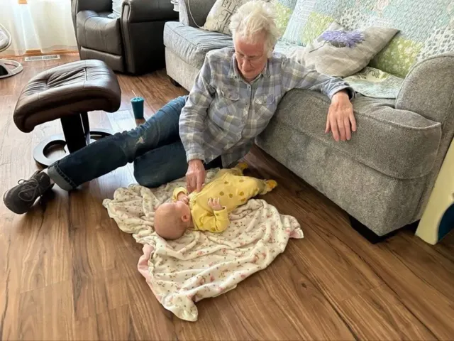 Resident visiting with a baby beside the sofa at AAA Shepherd’s Care Home