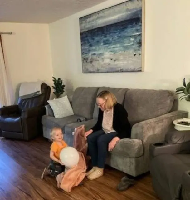 Staff member playing with a baby beside the sofa at AAA Shepherd’s Care Home